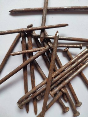 Beyaz arka planda dağınık paslı çiviler.