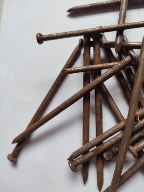 Beyaz arka planda dağınık paslı çiviler.