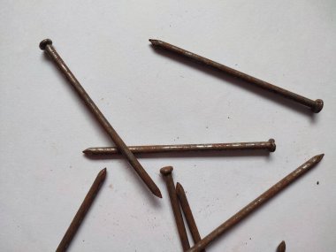 Beyaz arka planda dağınık paslı çiviler.