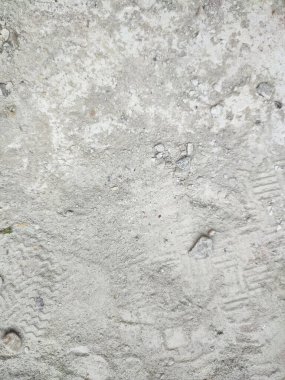 Yolun kenarındaki kum tepeleri gri bir arka planda kentsel bir ortamda güneş ışığıyla aydınlatılıyor.