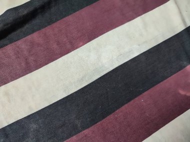 Kirli beyaz, siyah ve kırmızı kumaş altta ve tozla dolu.