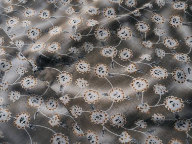 Arka plan çiçek desenli beyaz ve gri kumaştan oluşuyor.