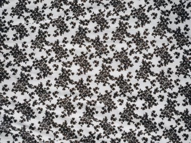 The pattern and background of the fabric is white with a small black flower motif clipart