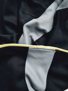 Kumaşın dokusu ve arkaplanı gri ve yeşil çizgilerle siyahtır.