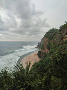 Temiz kumlu sahil manzarası, yüksek uçurumlar, güzel gökyüzü ve deniz dalgaları