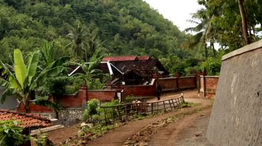 Güzel doğal manzarası ve tepeleri olan bir köyde yoldan geçen bir insan.