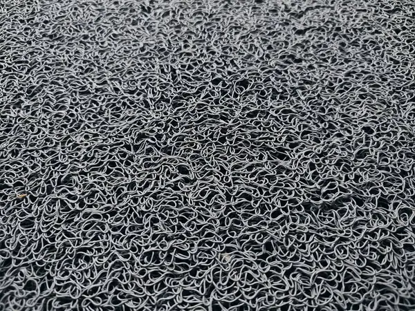 Genellikle kapının önüne konan gri bir hoş geldin paspası.