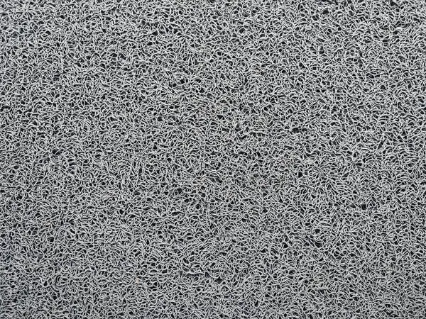 Genellikle kapının önüne konan gri bir hoş geldin paspası.