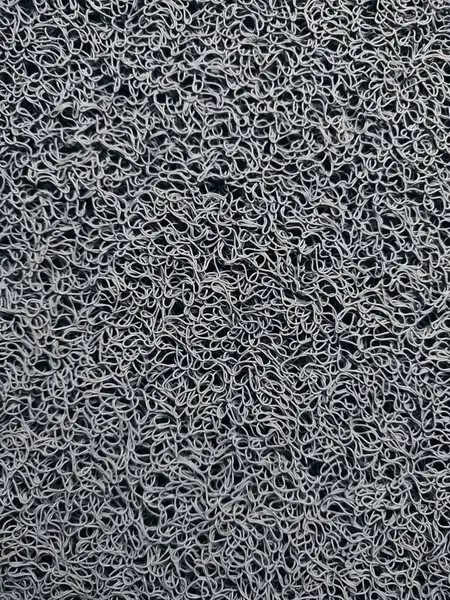 Genellikle kapının önüne konan gri bir hoş geldin paspası.