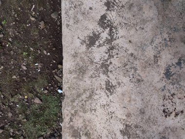 Asfalt ve toprak arkaplanı yosun, kaya ve kağıt parçalarıyla dolu.