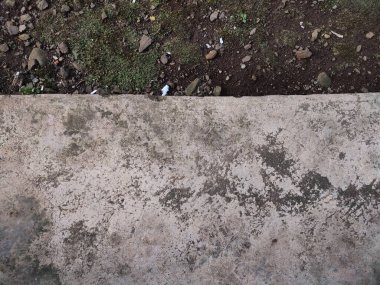 Asfalt ve toprak arkaplanı yosun, kaya ve kağıt parçalarıyla dolu.