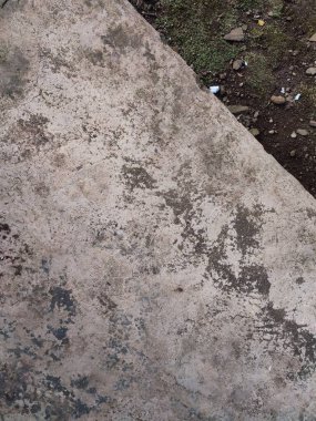 Asfalt ve toprak arkaplanı yosun, kaya ve kağıt parçalarıyla dolu.