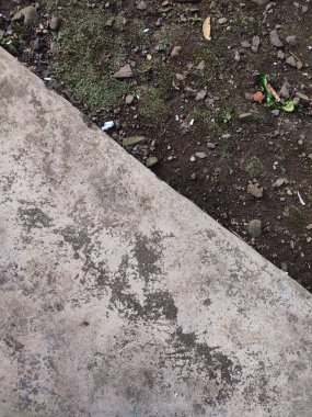 Asfalt ve toprak arkaplanı yosun, kaya ve kağıt parçalarıyla dolu.