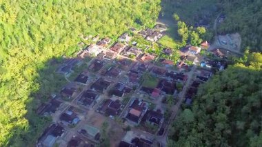 Tepeler ve yemyeşil ağaçlarla çevrili kırsal bir manzara.