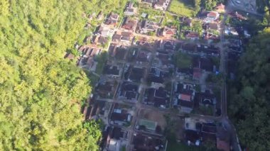 Tepeler ve yemyeşil ağaçlarla çevrili kırsal bir manzara.