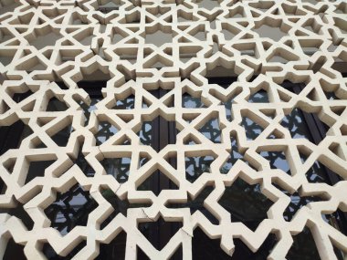 Parlak renkler ve simetrik desenler içeren detaylı bir İslami geometrik mozaik. Tasarım geleneksel arabesk motiflerini içerir.