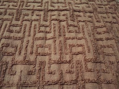Kahverengi havlunun dokusu ve arkaplanı labirente benzer kıvrım çizgisi desenine sahip.