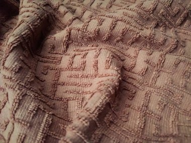 Kahverengi havlunun dokusu ve arkaplanı labirente benzer kıvrım çizgisi desenine sahip.