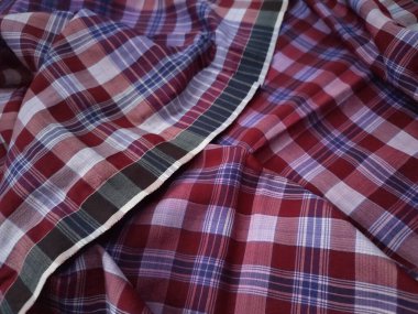 The pattern and background of the fabric is a checkered material in purple, red, brown and white.