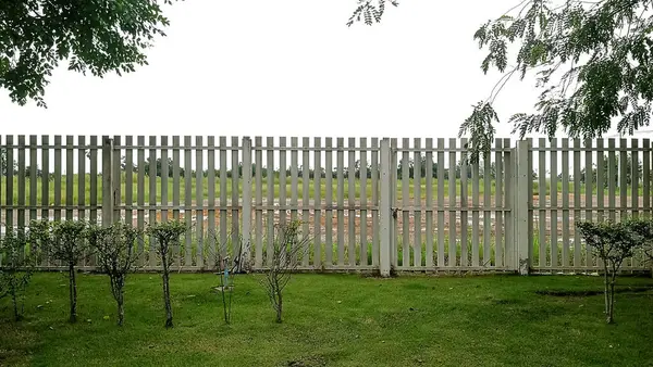 a wooden fence in the middle of a grassy yard, fence, wooden fence
