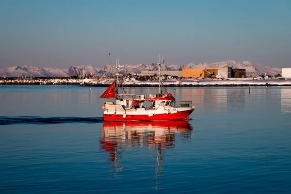 Red fishing boat coming back to harbour in norway. High quality photo.