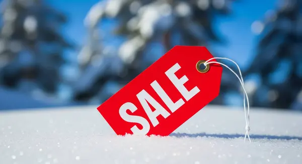 Beyaz harfli parlak kırmızı bir etiket ışıl ışıl kar yatağında duruyor. Arka planda bulanık kış ağaçları açık mavi bir gökyüzüne karşı duruyor..