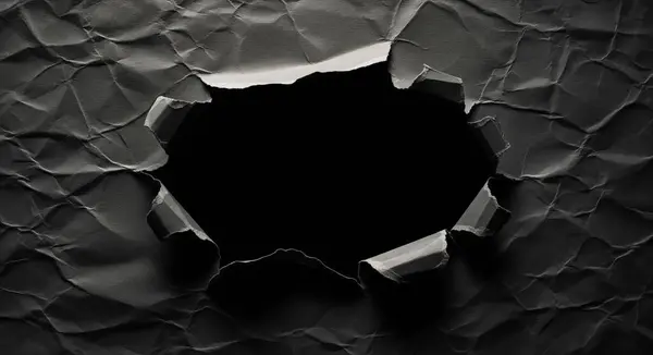 Merkezinde büyük, pürüzlü bir yırtık olan buruşuk siyah kağıdın yakın çekim görüntüsü derin siyah bir boşluğu ortaya çıkarıyor. Kağıdın dokusu ve gölgeleri vurgulanıyor.