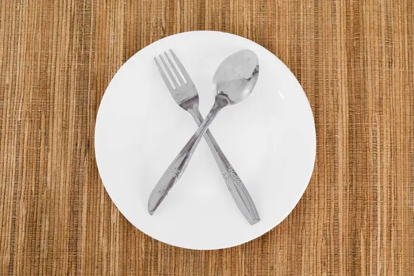 Tahta masada çatal ve kaşıkla boş tabak.