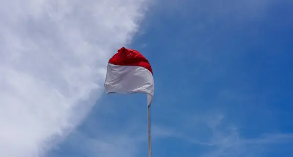 Mavi gökyüzünde dalgalanan Endonezya bayrağı.