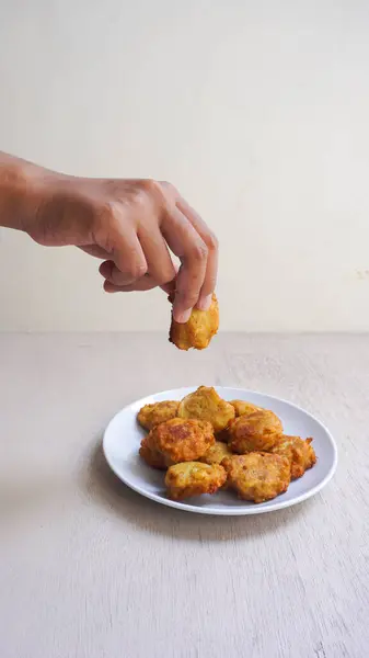 Beyaz arka planda bir tabak kızarmış patates cipsi tutan birinin yakın plan fotoğrafı.