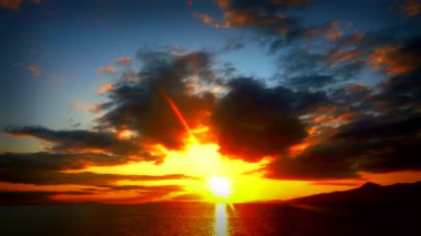 Batan güneşin nefes kesen manzarası, bulutların arkasında kaybolan, turuncu renkli gökyüzünü boyayan..