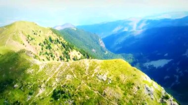 İnsansız hava aracı, dağ sırasının yemyeşil zirvelerini nefes kesici bir şekilde yakalıyor ve yukarıdan büyüleyici bir doğa güzelliği sergiliyor..