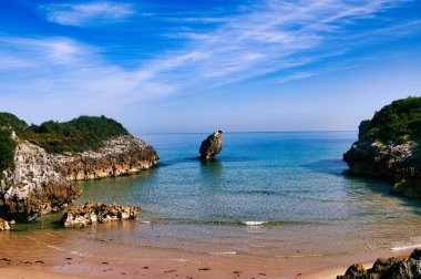 Turkuaz suyu, kayaları ve mavi gökyüzü olan güzel bir sahil.