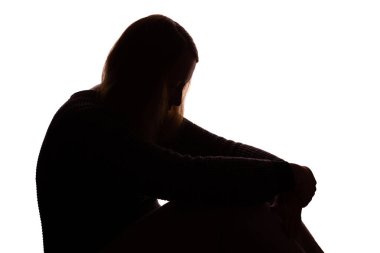 Uzun, gevşek saçlı, kafası derin bir üzüntü ve duygusal acıyla eğik yalnız oturan genç bir kadının koyu renk silüeti. Beyaz arka planda izole edilmiş. Görüntü, depresyon, yalnızlık ve zihinsel sağlık mücadelesini çağrıştırıyor..
