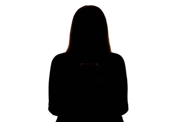 Silhouette of a young woman holding a smartphone and looking at the screen. Isolated on a white background. The scene suggests themes of modern communication, technology, solitude, and personal reflection. Clean and minimalist composition.