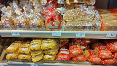 Dnipro, Ukrayna - 09 Nisan 2025: Süpermarket vitrininde taze ekmek ve çörek çeşitleri. Günlük temel ihtiyaçlar kavramı, market alışverişi, yiyecek çeşitliliği.