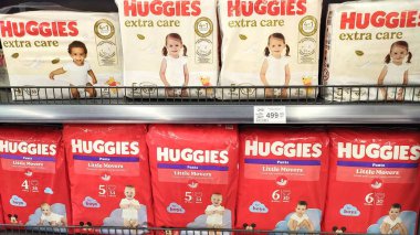 Dnipro, Ukrayna - 09 Nisan 2025: Çeşitli bebekler raftaki bebek bezi paketlerinde gülümsüyor. Bebek bakımı kavramı, pazarlamada çeşitlilik, tüketici tercihleri, şımartıcılar.