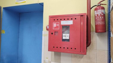 İtfaiye hortumu ve yangın söndürücü de dahil olmak üzere yangın güvenlik ekipmanları süpermarketin duvarına monte edildi. Acil durum hazırlığı kavramı, yangın koruma sistemi.