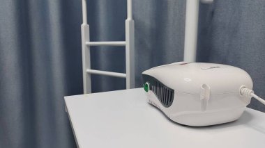 Dnipro, Ukrayna - 26 Nisan 2025 - Tıbbi nebulizer makinesi hastane odasındaki masada tıbbi ekipmanlarla birlikte. solunum terapisi, sağlık tedavisi, solunum desteği, astım tedavisi.