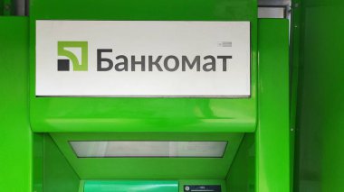 Dnipro, Ukrayna - 26 Nisan 2025 - Kiril alfabesiyle gösterilen açık yeşil atm makinesi. Modern bankacılık teknolojisi kavramı, finansal erişim, şehir kolaylığı.