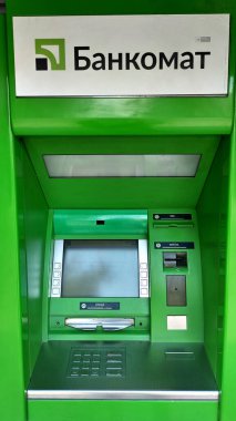 Dnipro, Ukrayna - 26 Nisan 2025 - Açık havada Kiril arayüzü olan yeşil atm makinesi. Bankacılık konsepti, finansal işlemler, ATM kullanımı. Dikey.