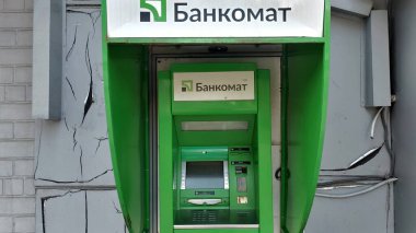 Dnipro, Ukrayna - 26 Nisan 2025 - Kırık duvarlı yeşil ATM makinesi. Kamu alanlarında modern teknoloji kavramı, günlük kolaylık, kentsel zorluklar.