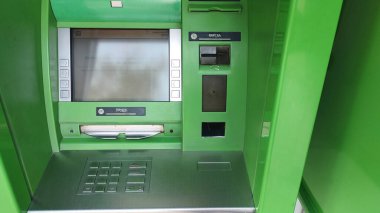 Dnipro, Ukrayna - 26 Nisan 2025 - Şehir ortamında etkileşimli dokunmatik ekranlı yeşil ATM. Modern bankacılık kolaylığı kavramı, finansal işlemler, güvenilir teknoloji.