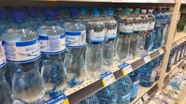 Dnipro, Ukrayna - 26 Nisan 2025 - çeşitli boyutlarda ve markalarda süpermarket raflarında sergilenen maden ve içme suyu şişeleri. Sağlıklı su tüketimi, market alışverişi, içecek bölümü kavramı.