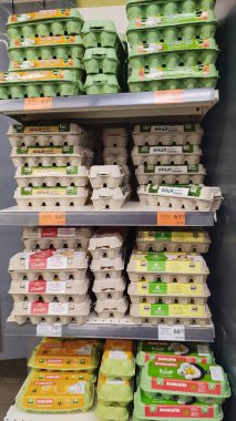 Dnipro, Ukrayna - 26 Nisan 2025 - market raflarında fiyat etiketleriyle çeşitli yumurta kutuları. Alışveriş konsepti, çeşitli seçenekler, süpermarkette günlük temel ihtiyaçlar. Dikey.