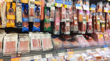 Dnipro, Ukrayna - 26 Nisan 2025 - Süpermarket raflarında sergilenen tedavi edilmiş ve tütsülenmiş sosis ve dilimlenmiş et çeşitleri. Market alışverişi, meze bölümü, korunmuş et ürünleri kavramı.
