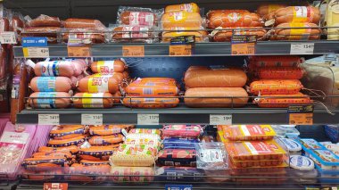 Dnipro, Ukrayna - 26 Nisan 2025 - Dondurulmuş süpermarket raflarında renkli plastik paketlerde haşlanmış sosisler ve frankfurtların çeşitli çeşitleri. Hazır et konsepti, market alışverişi..
