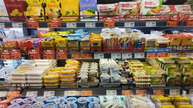 Dnipro, Ukrayna - 26 Nisan 2025 - Dondurulmuş süpermarket raflarında sergilenen renkli ambalajlarda sert, işlenmiş ve krem peynirlerden oluşan geniş bir seçim. Süt ürünleri, market alışverişi kavramı.