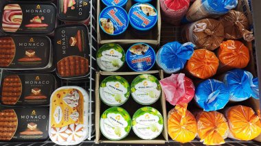 Dnipro, Ukrayna - 26 Nisan 2025 - Süpermarket dondurucusunda sergilenen dondurma küvetleri, fincanlar ve yumuşak paketler de dahil olmak üzere çeşitli dondurulmuş tatlılar. Tatlı ikram kavramı, market alışverişi..