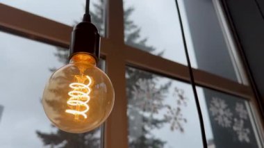 Beautiful loft-style lamp on a cloudy window background hot spiral of tungsten bulb. High quality 4k footage